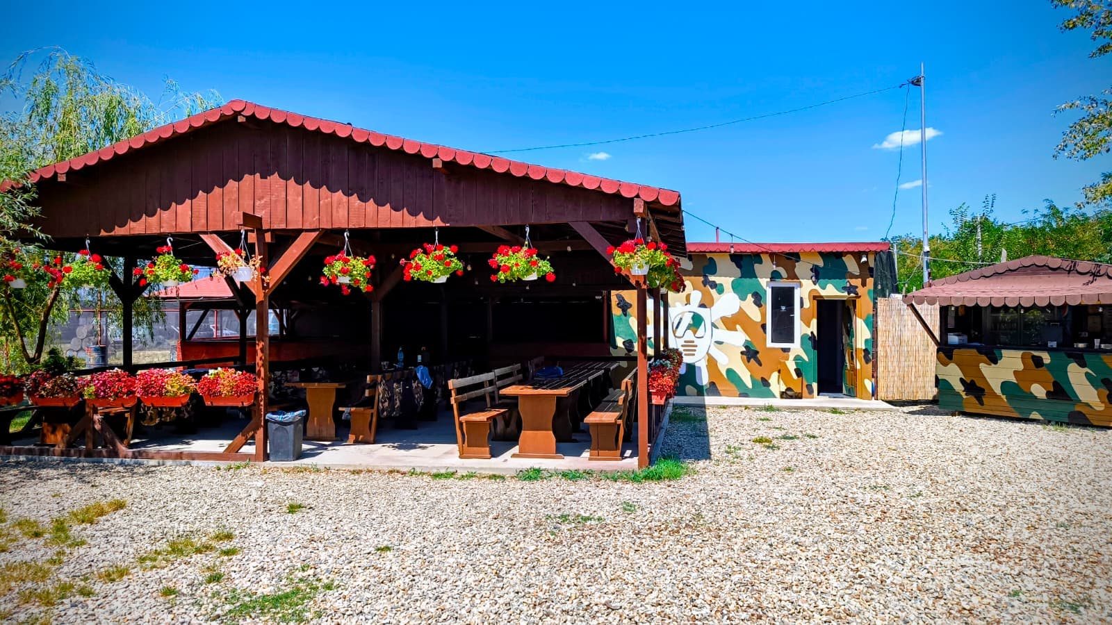 Covered terrace with wooden tables and flowers, the Paintball Hunter relaxation area, Chiajna